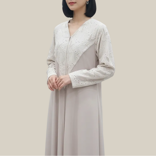 Woman in a long, light-colored dress standing in a clothing store.